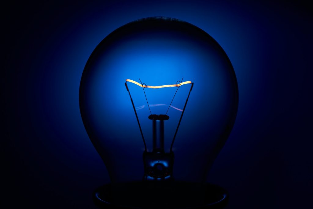 Electric bulb lamp with a spiral on a blue background
