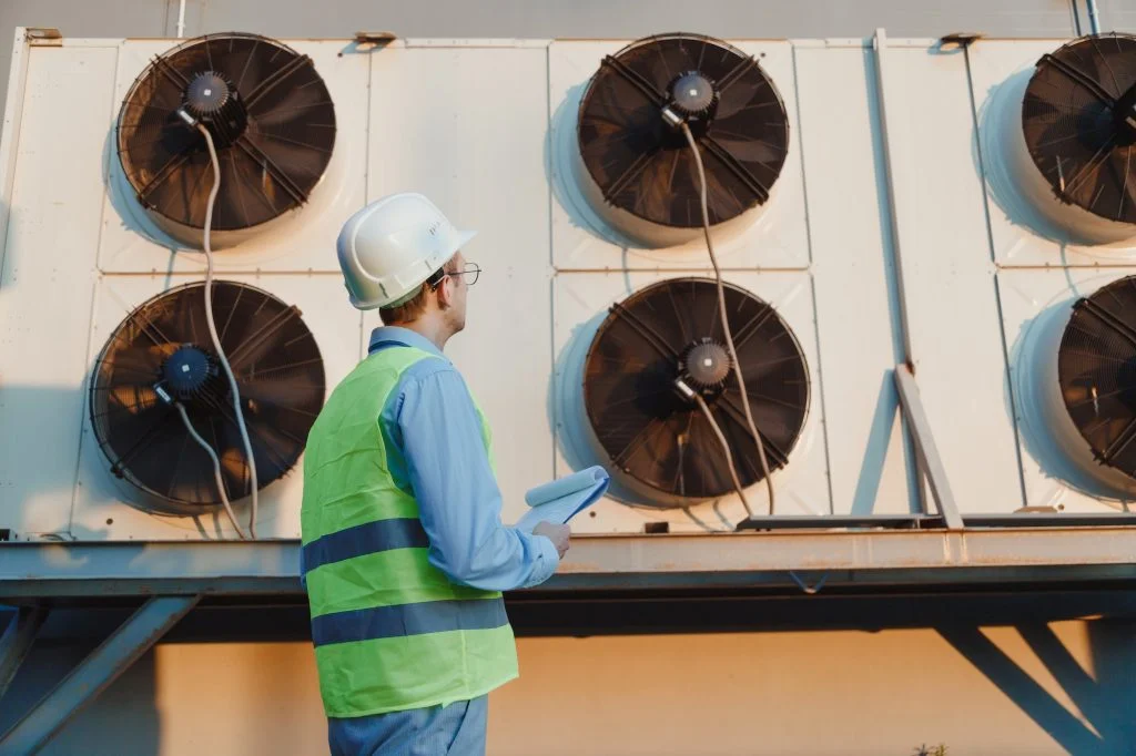 Service hvac engineer in uniform inspecting industrial refrigeration system