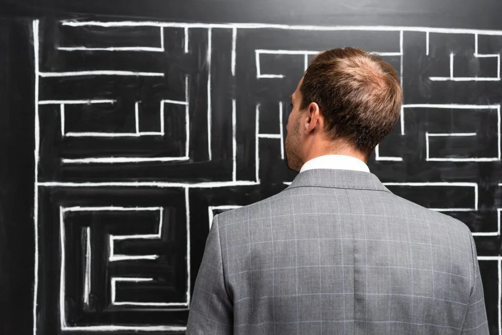 back view of businessman in suit looking at labyrinth