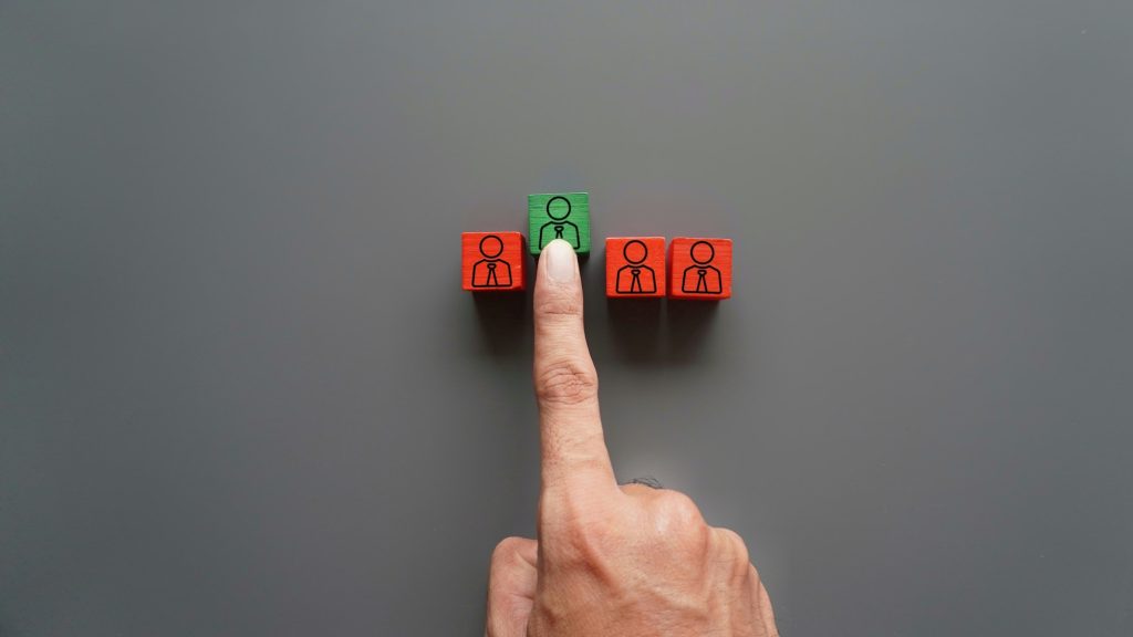 Hand choose green wooden cube with people icon.