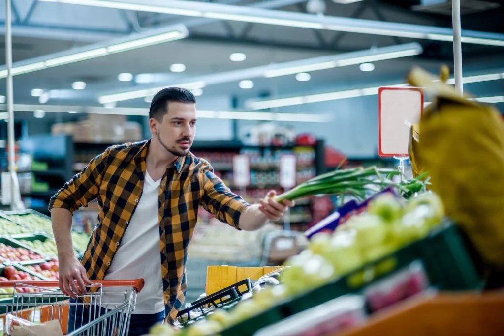 Young handsome man in a supermarket grocery shopping
