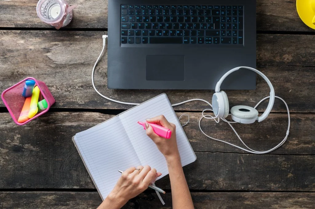 Female hands making notes in notepad and marking importance with pink marker