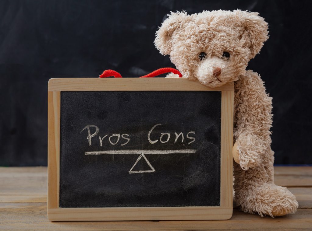 Pros contra cons, teddy bear holds a framed chalkboard with empty list on, blackboard background.
