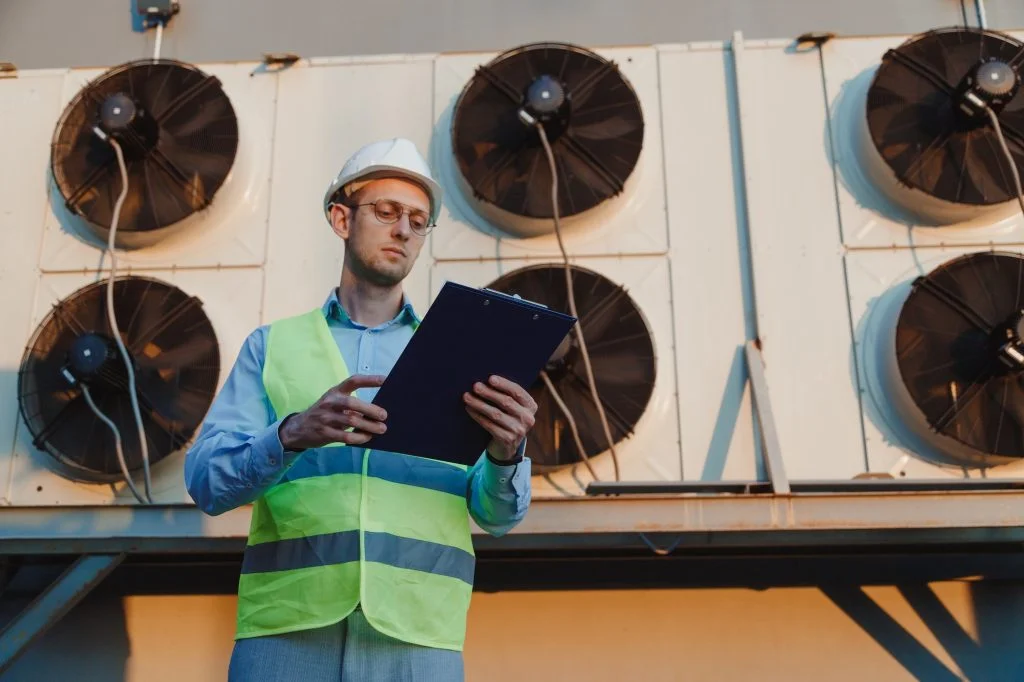 Service hvac engineer in uniform inspecting industrial refrigeration system