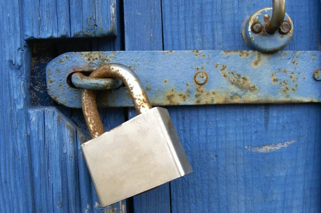 Old Lock on Blue Wood Door. Old-fashioned latch on the door, retro style. Old closed padlock rusty