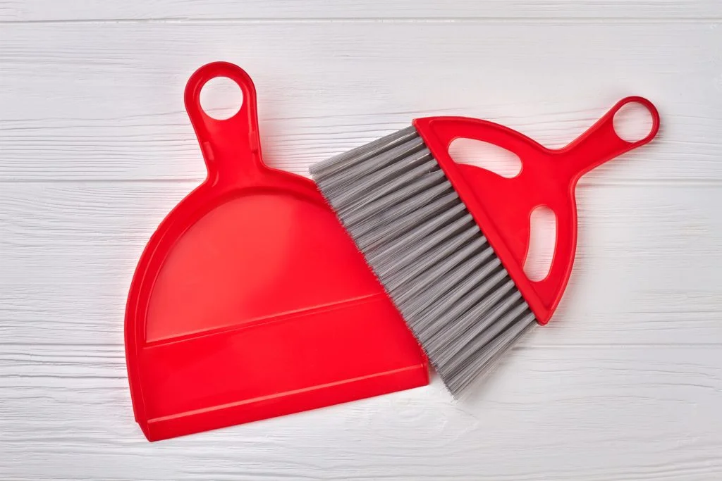 Brush and dustpan on wooden background.